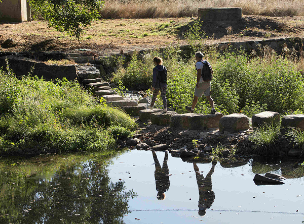 Couple crossing stream on stone path
